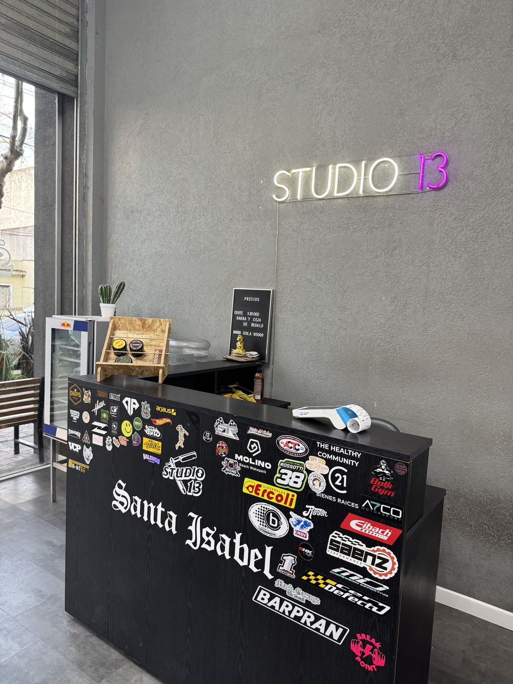 El mostrador con stickers y el neón de Studio 13